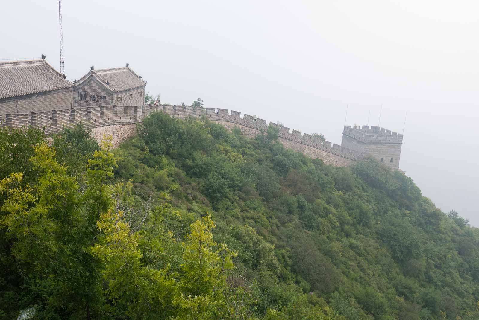 Great Wall of China, shrouded in mist and surrounded by greenery.