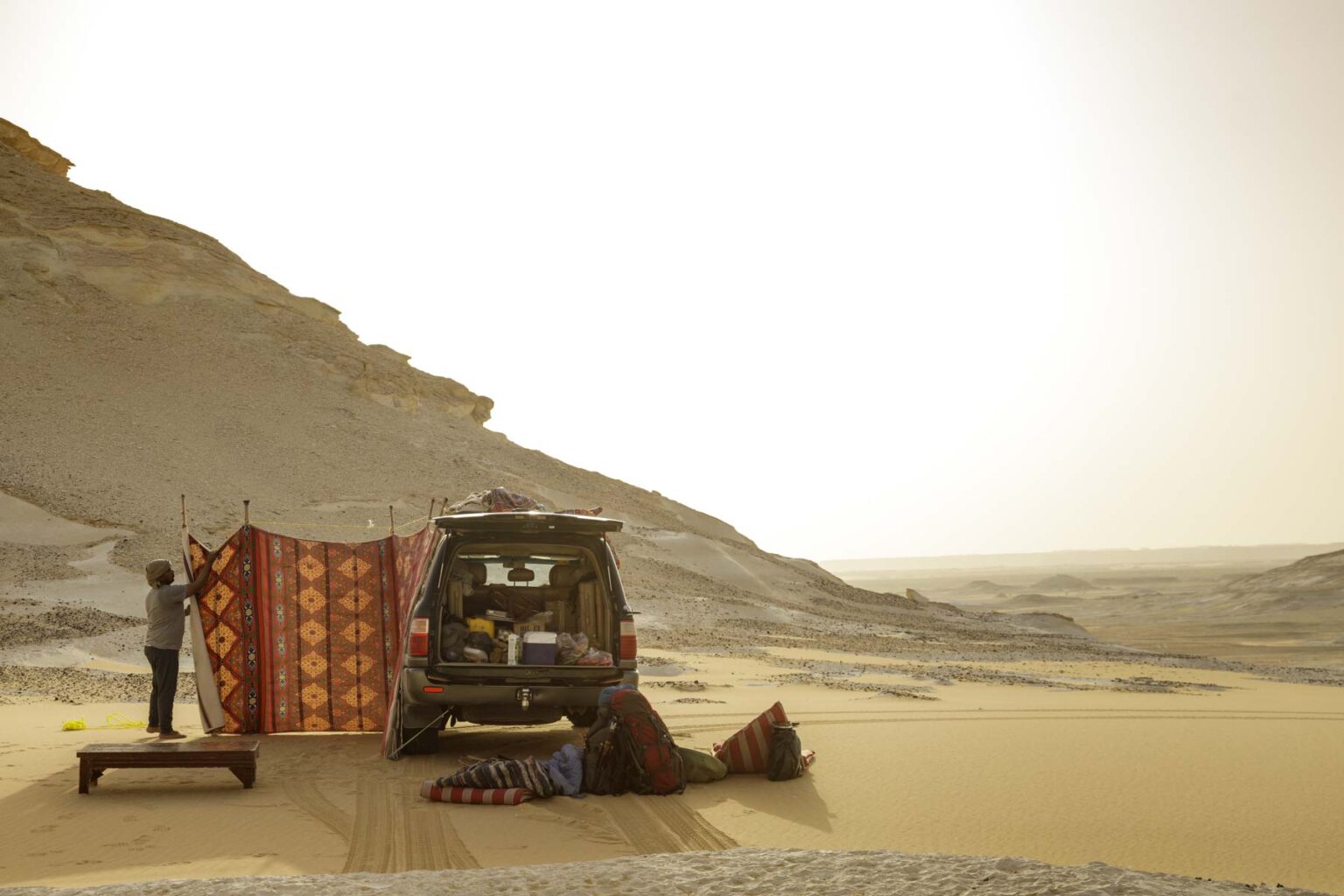 A four-wheel drive sits next to a Bedouin tent at dusk in the White Desert.