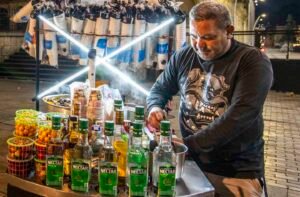A man with spirits filling a cart makes canalazo on the street in Bogota.